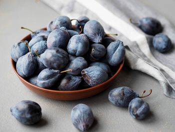 Large autumn blue plums lie in a natural clay bowl. natural fruits from the garden.