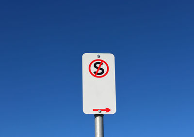 Low angle view of no standing sign against clear blue sky