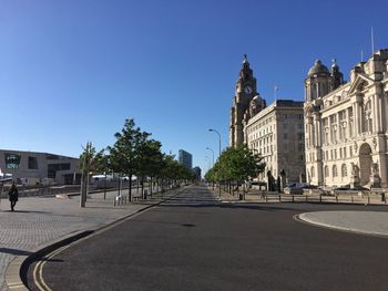 Street amidst buildings against blue sky