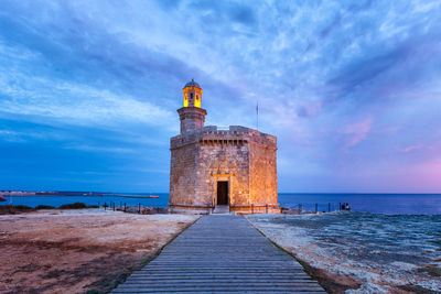 Castle at beach against cloudy sky