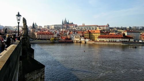 View of buildings by river against sky in city