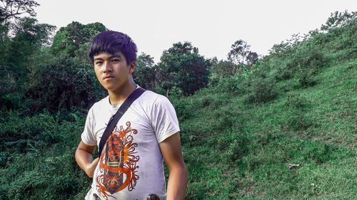 Portrait of young man standing against trees