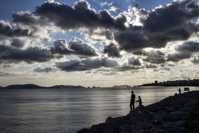 Man fishing in sea against sky