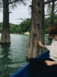 Woman sitting on tree trunk by lake