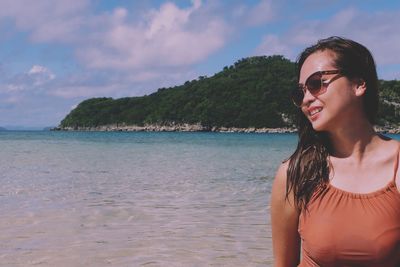 Portrait of smiling young woman at beach against sky