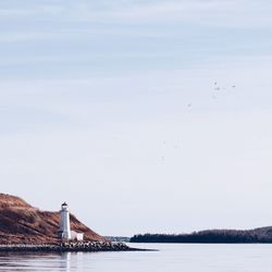 Lighthouse by river against sky