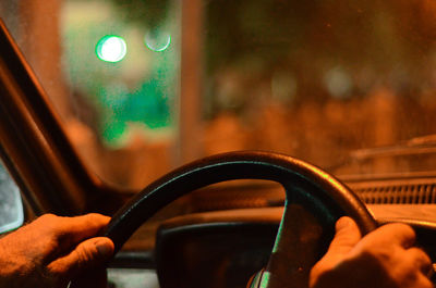 Cropped hand of man driving car at night