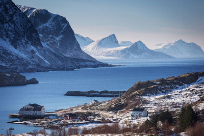 Scenic view of sea by snowcapped mountains against sky