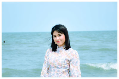 Portrait of smiling woman standing against seascape and sky