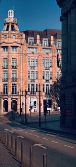 Road by buildings against sky in city