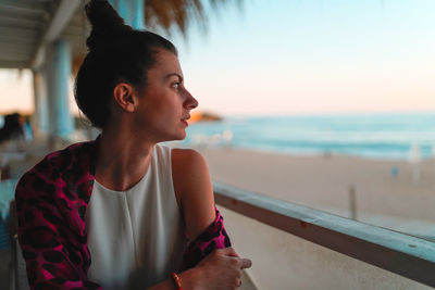 Young woman looking away while standing at beach