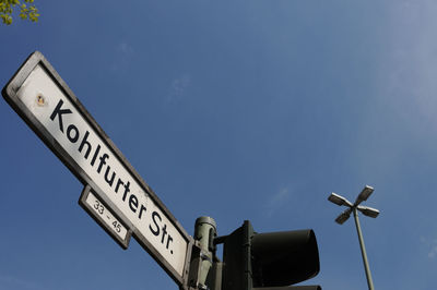 Low angle view of road sign against clear blue sky