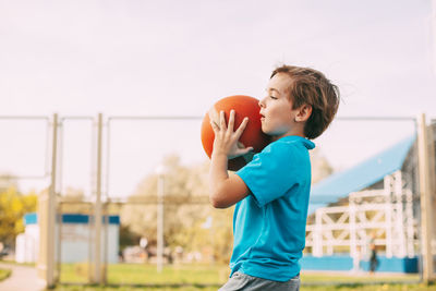 Boy playing with basketball against clear sky
