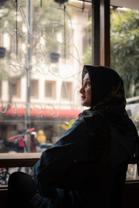 Side view of man looking through window