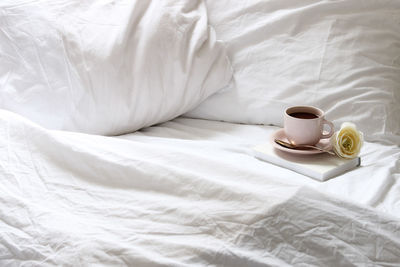 Coffee in cup on bed at home