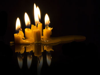 Close-up of burning candle against black background