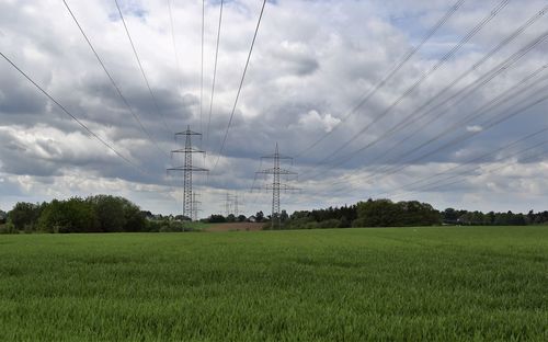 Electricity pylon on field against sky