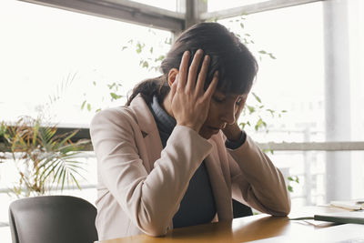 Exhausted businesswoman sitting with head in hands at office