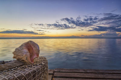 Pier over lake against sky during sunset