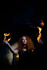 Portrait of young woman with fire in the dark