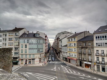 Street and buildings in city against cloudy sky