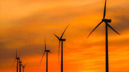 Low angle view of electricity pylon against sky during sunset,wind turbine