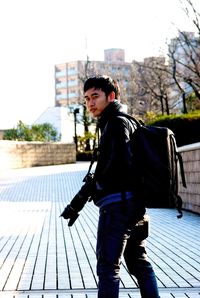 Full length of young man standing against sky in city