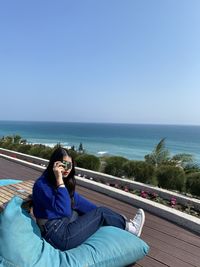 Young woman relaxing on blue sea against clear sky