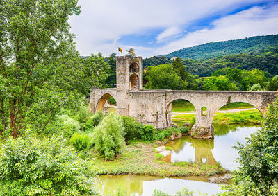 Arch bridge over river against sky