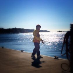 Full length of woman standing on shore against clear sky