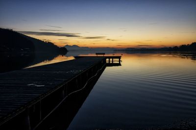 Pier over lake against sky during sunset