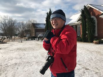 Cheerful photographer standing on snow