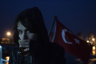 Close-up portrait of young man having drink against sky at night