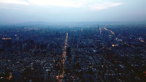 High angle view of illuminated buildings in city at dusk against sky