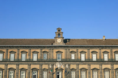 Low angle view of clock building against blue sky