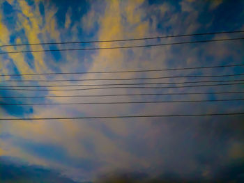 Low angle view of power lines against sky