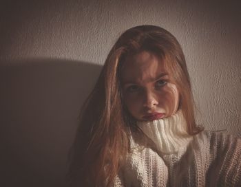 Close-up portrait of a young woman against wall