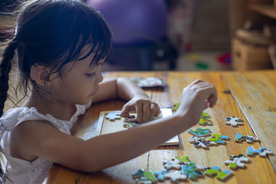 Cute girl holding toy toys on table