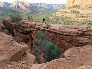 Rear view of man standing on rock against sky