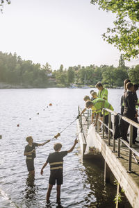 Volunteers cleaning plastic from lake against sky