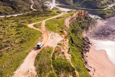 Aerial view of a four wheel drive car parked on the top of the cliff facing the atlantic ocean