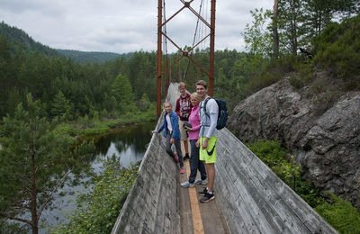 Rear view of girls on footbridge against sky