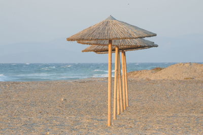 Row of thatched parasols at beach against sky