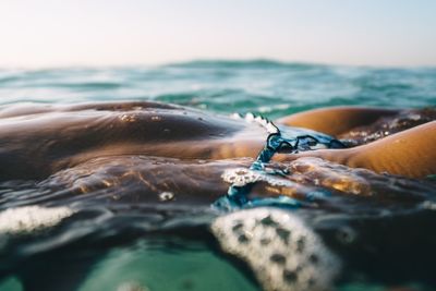 Midsection of woman in bikini swimming in sea