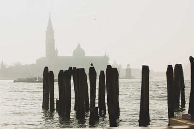 Wooden posts in sea against clear sky