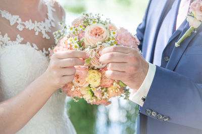 Midsection of couple holding flower bouquet