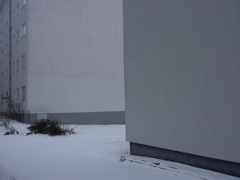Snow covered field by building against sky