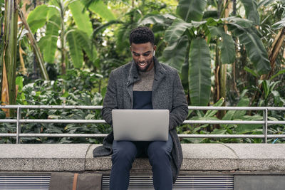 Young man using laptop while sitting outdoors