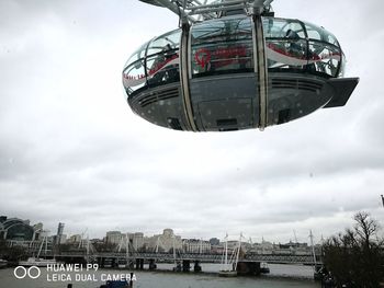 Ferris wheel by river against sky in city