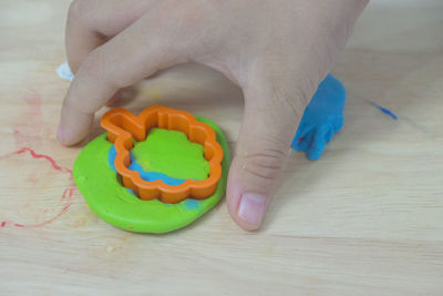 Cropped hand of person playing with clay on table at home